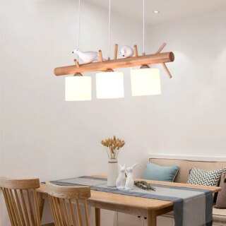 On voit un lustre en bois avec deux oiseaux et trois supensions au dessus d'une salle à manger