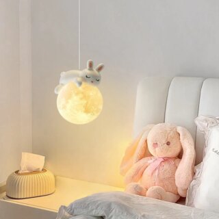 On voit un lustre suspendu avec une boule lumineuse qui représente la lune et un lapin qui dort dessus.