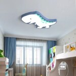 On voit un lustre plafonnier à l'effigie d'un dinosaure bleu, dans une chambre d'enfant.