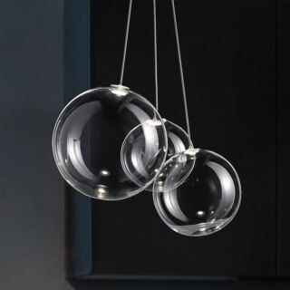 On voit un lustre avec 3 suspensions en verre sur un fond noir.
