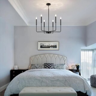 Photo d'un lustre bougie noir à six branches de style minimaliste moderne dans une chambre à coucher aux tons gris bleu au dessus d'un grand lit habillé de gris et plafond blanc