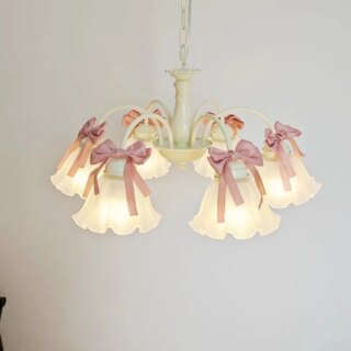 Photo d'un lustre pour chambre de fille vert d'eau à six corolles festonnées tête en bas au style art nouveau avec des rubans roses noués au dessus des corolles suspendu devant un mur gris