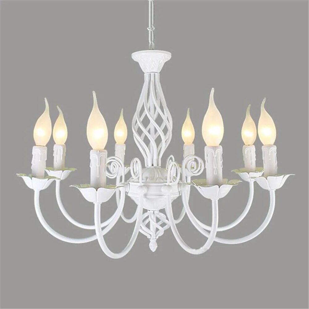 Photo d'un lustre chandelier en fer forgé blanc à huit branches courbées et huit ampoules bougies allumées, avec un corps travaillé en forme de vase tête en bas, le tout sur un fond gris