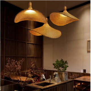 Photo de trois lustres en forme de chapeau, les trois mêmes vis sous des angles différents allumés et suspendus dans une salle aux meubles foncés en bois avec un petit lavabo devant et des plantes, un mur gris foncé à droite