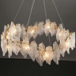 Photo d'un lustre chic couleur cuivre ondulé avec des feuilles de verre tout autour suspendu dans une pièce aux murs foncés