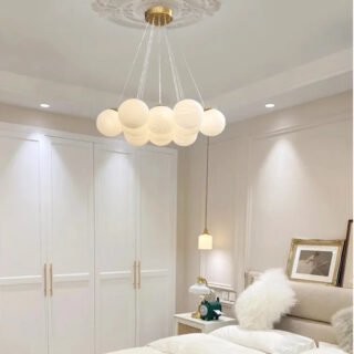 Photo d'un lustre boule suspendu dans une chambre avec un mur rose pale et un grand dressing blanc, un lit avec des coussins blancs également