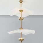 Photo d'un lustre original doré aux abat-jour blancs avec deux ampoules sur un fond blanc en haut et gris en bas